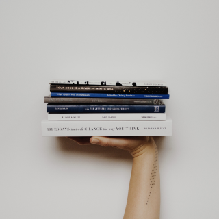 A hand holding up several books