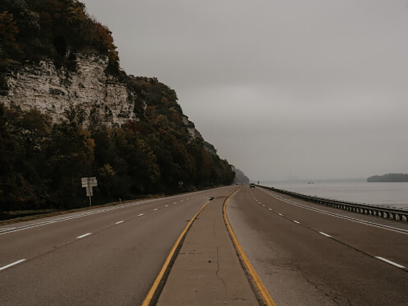 Highway between a mountain and body of water